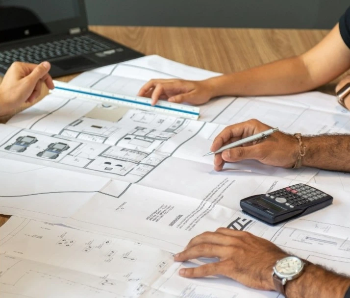 Proyecto de construcción con planos técnicos, escalímetro y calculadora sobre una mesa de trabajo en Madrid