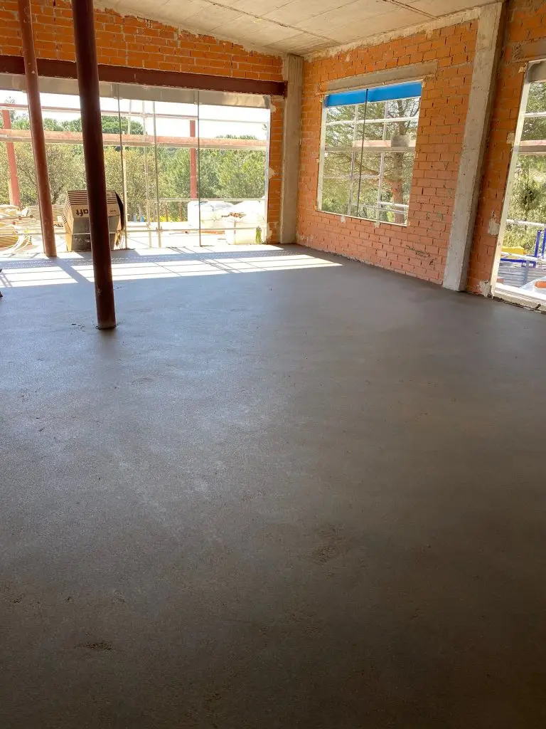 Construcción de suelo de hormigón nivelado en una vivienda con paredes de ladrillo en Madrid