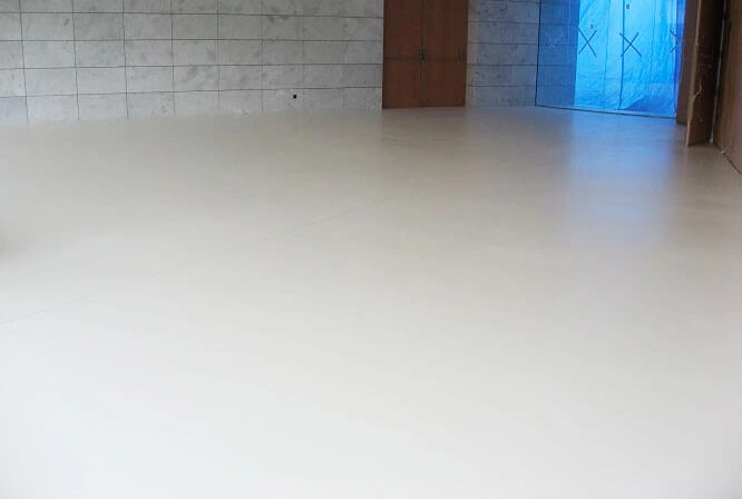 Construcción de suelo de microcemento blanco continuo en una estancia con paredes alicatadas en Madrid