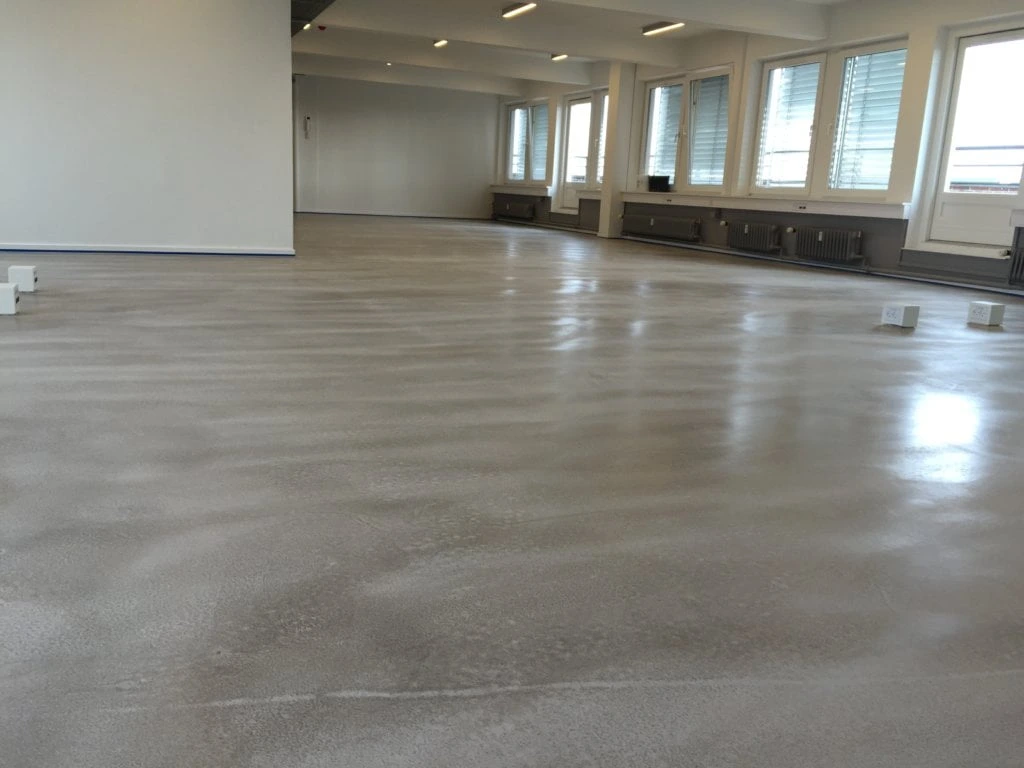 Construcción de suelo de microcemento gris con acabado continuo y brillante en un local de Madrid