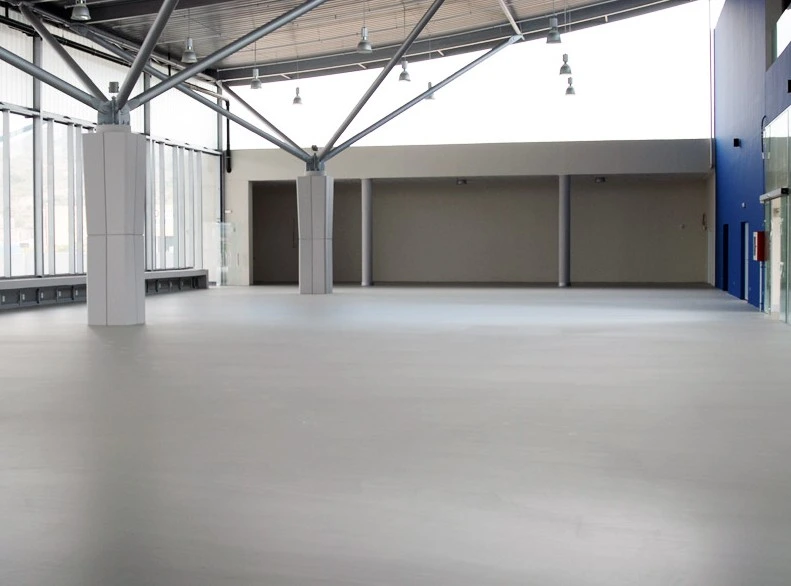 Construcción de nave industrial con suelo de resina gris y estructura metálica vista en Madrid