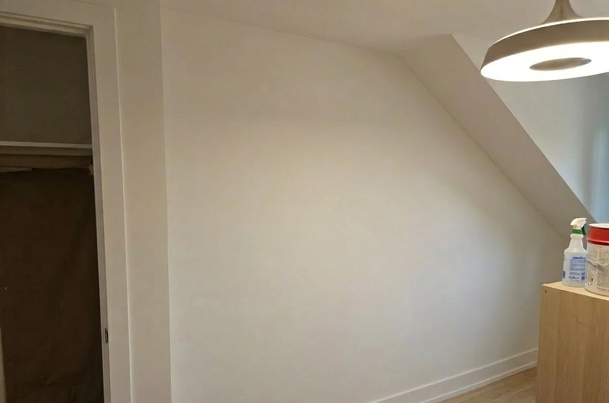 Servicio de pintura en pared abuhardillada blanca con rodapié a juego en Madrid