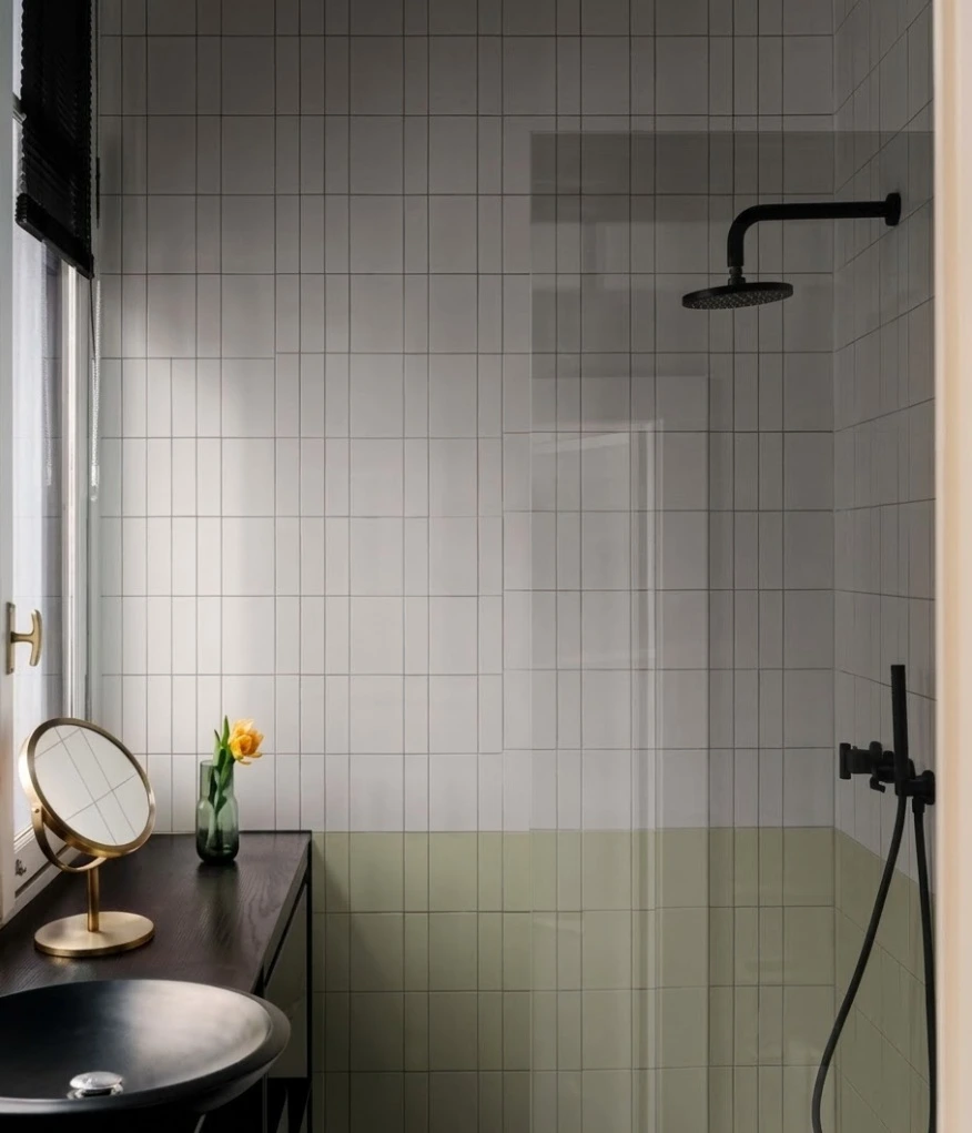 Reforma de baño con alicatado vertical bicolor y grifería negra mate en Madrid