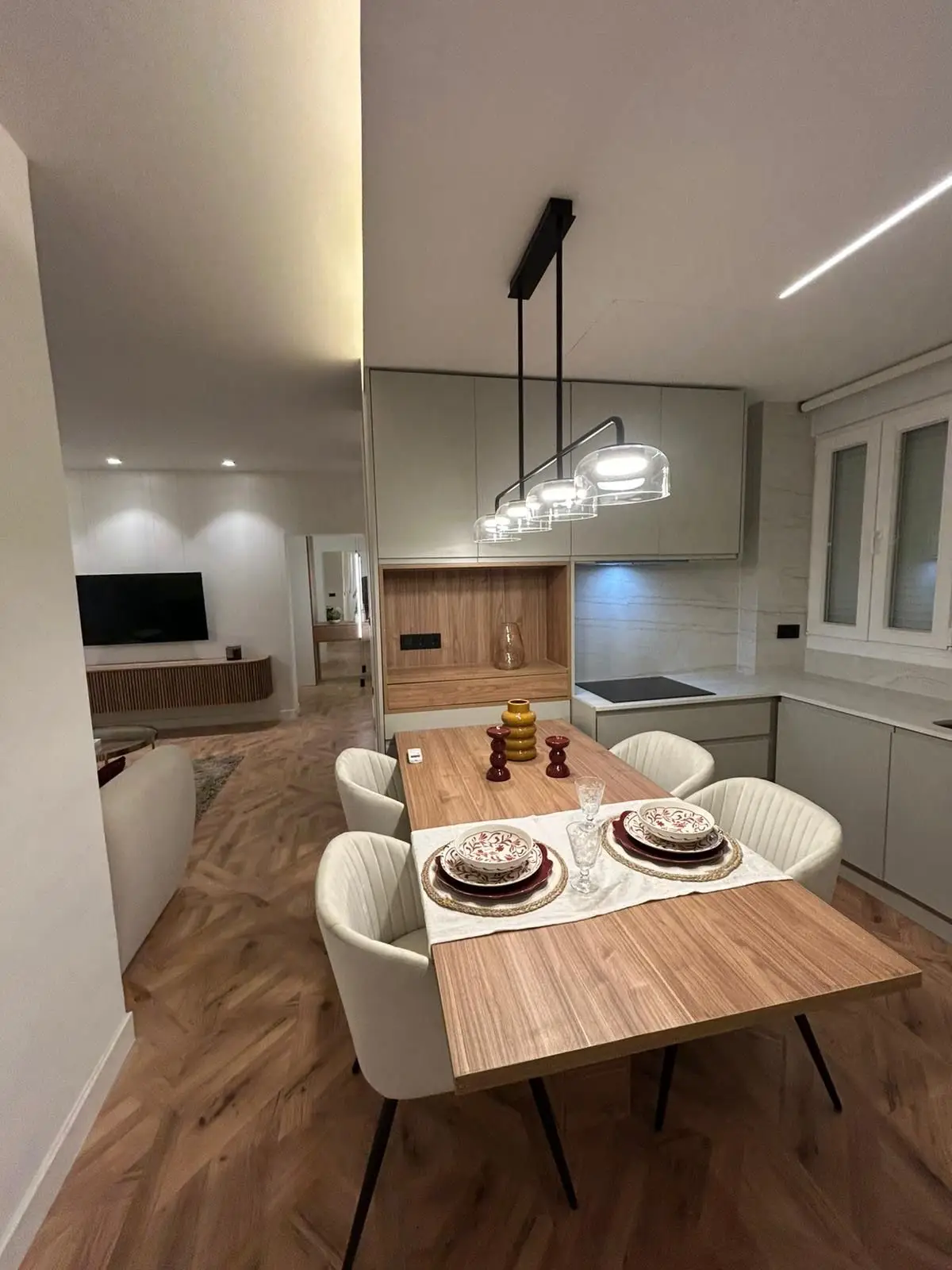 Reforma de cocina abierta con mesa de madera, sillas blancas y suelo de parqué en Madrid