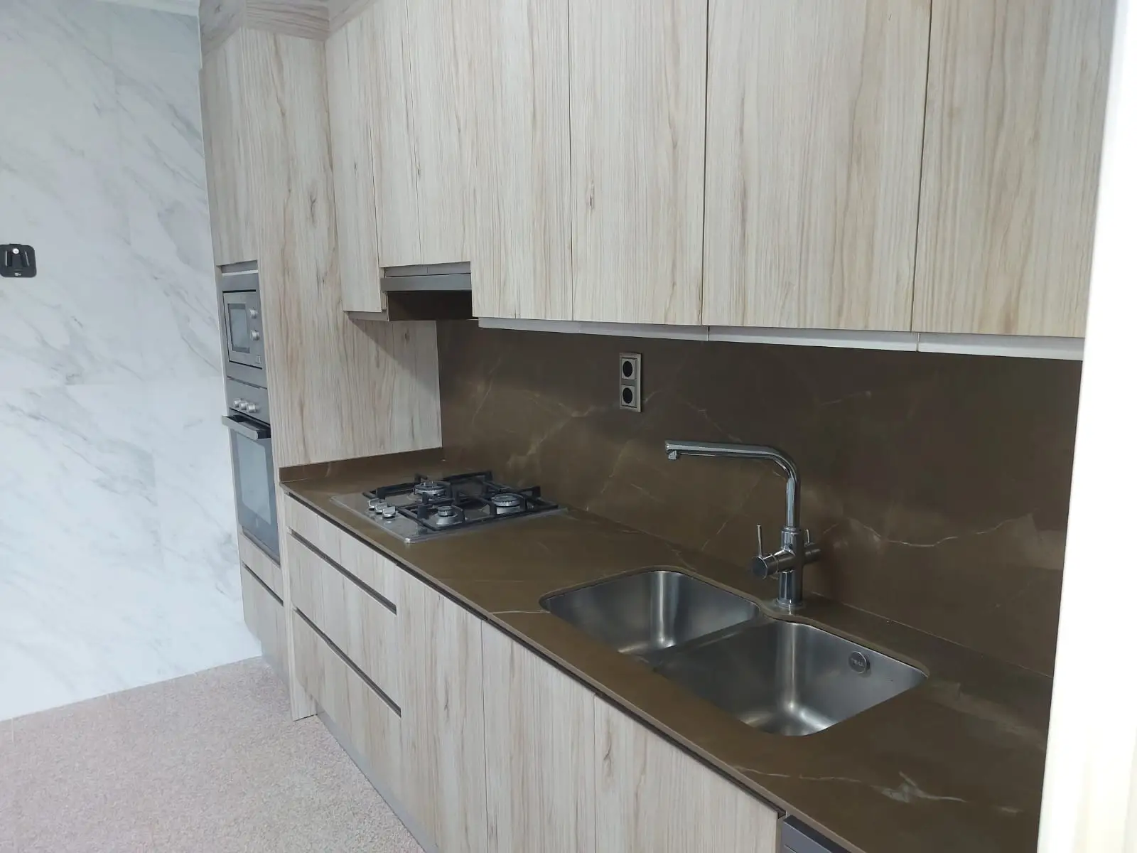 Reforma cocina con armarios de madera clara, encimera marrón y fregadero de acero inoxidable en Madrid