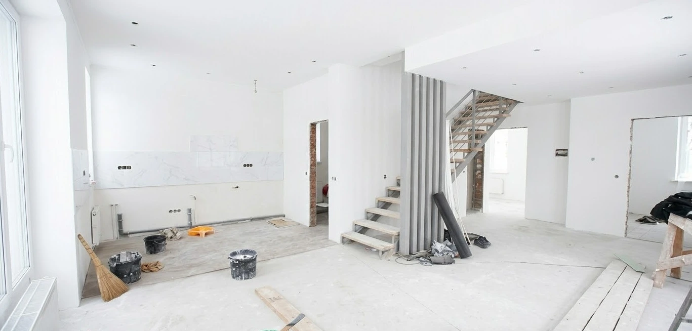 Reforma integral de vivienda en proceso con escalera metálica y paredes blancas en Madrid