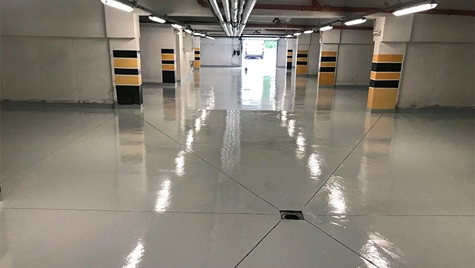 Rehabilitación de suelo de garaje con resina epoxi gris brillante y columnas señalizadas en Madrid