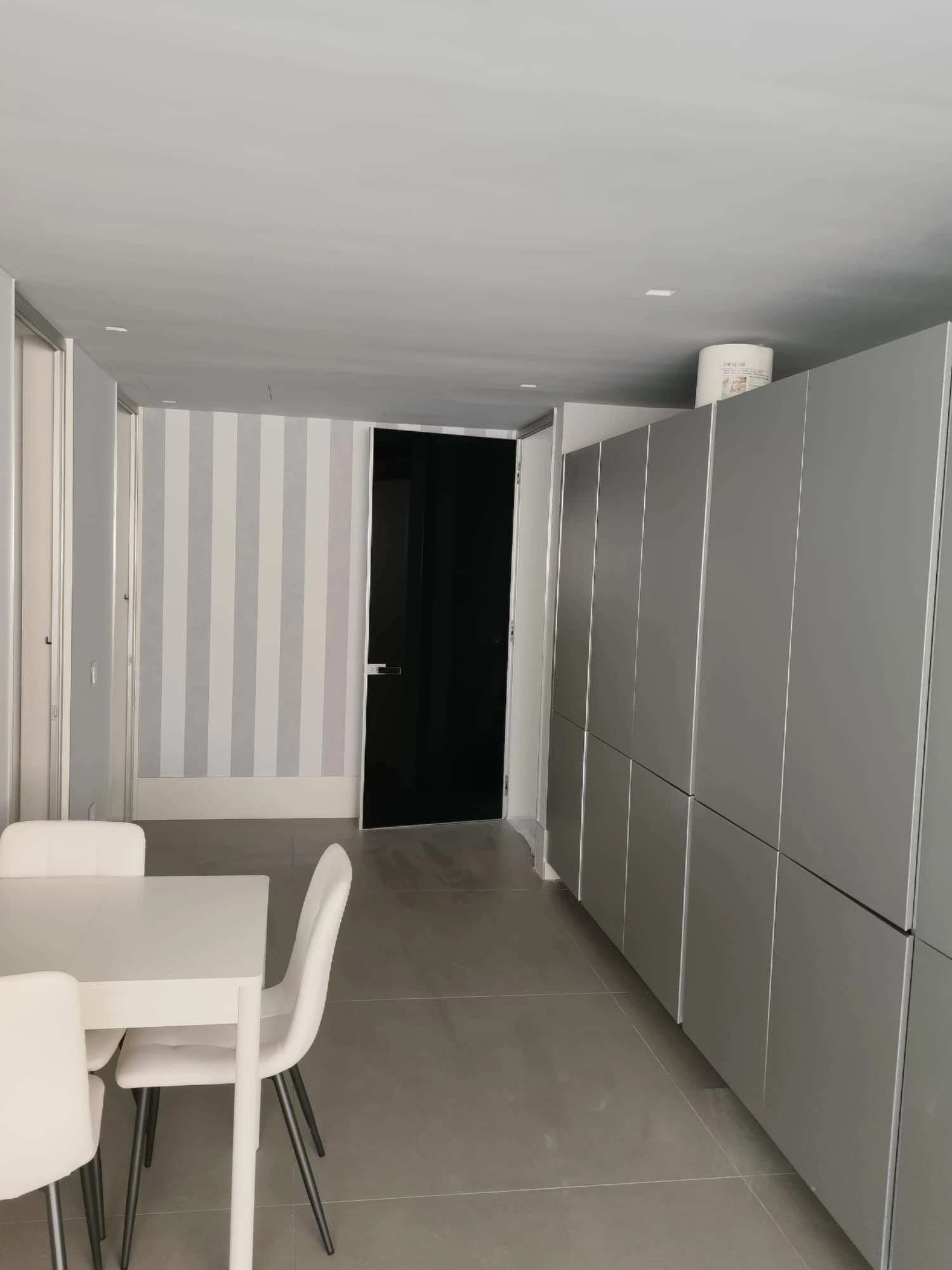Reforma vivienda con armarios empotrados grises y pared decorada con papel pintado de rayas en Madrid