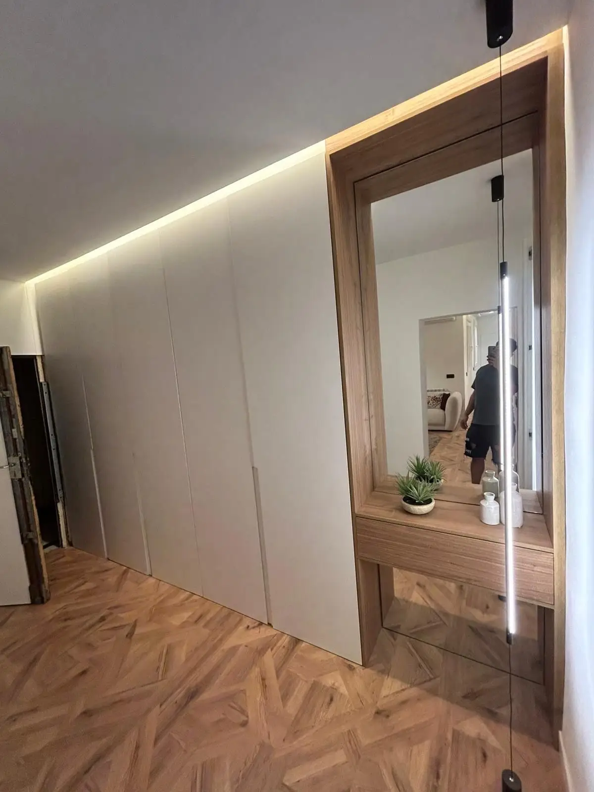 Reforma de vivienda con armarios empotrados blancos, iluminación LED integrada y tocador de madera en Madrid