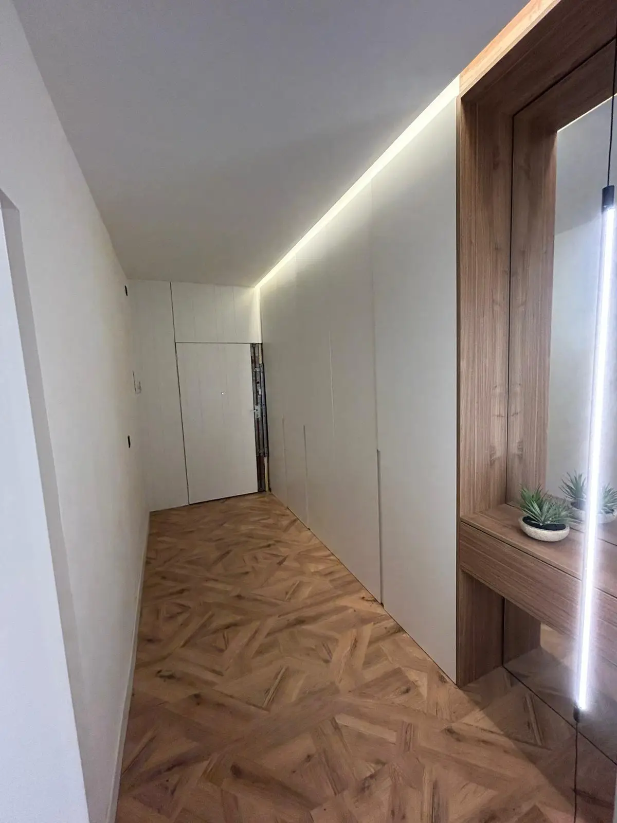 Reforma de vivienda con armarios empotrados blancos, iluminación LED indirecta y suelo laminado geométrico en Madrid