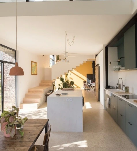 Reforma de cocina abierta con isla de microcemento blanco y mobiliario verde oliva en Madrid