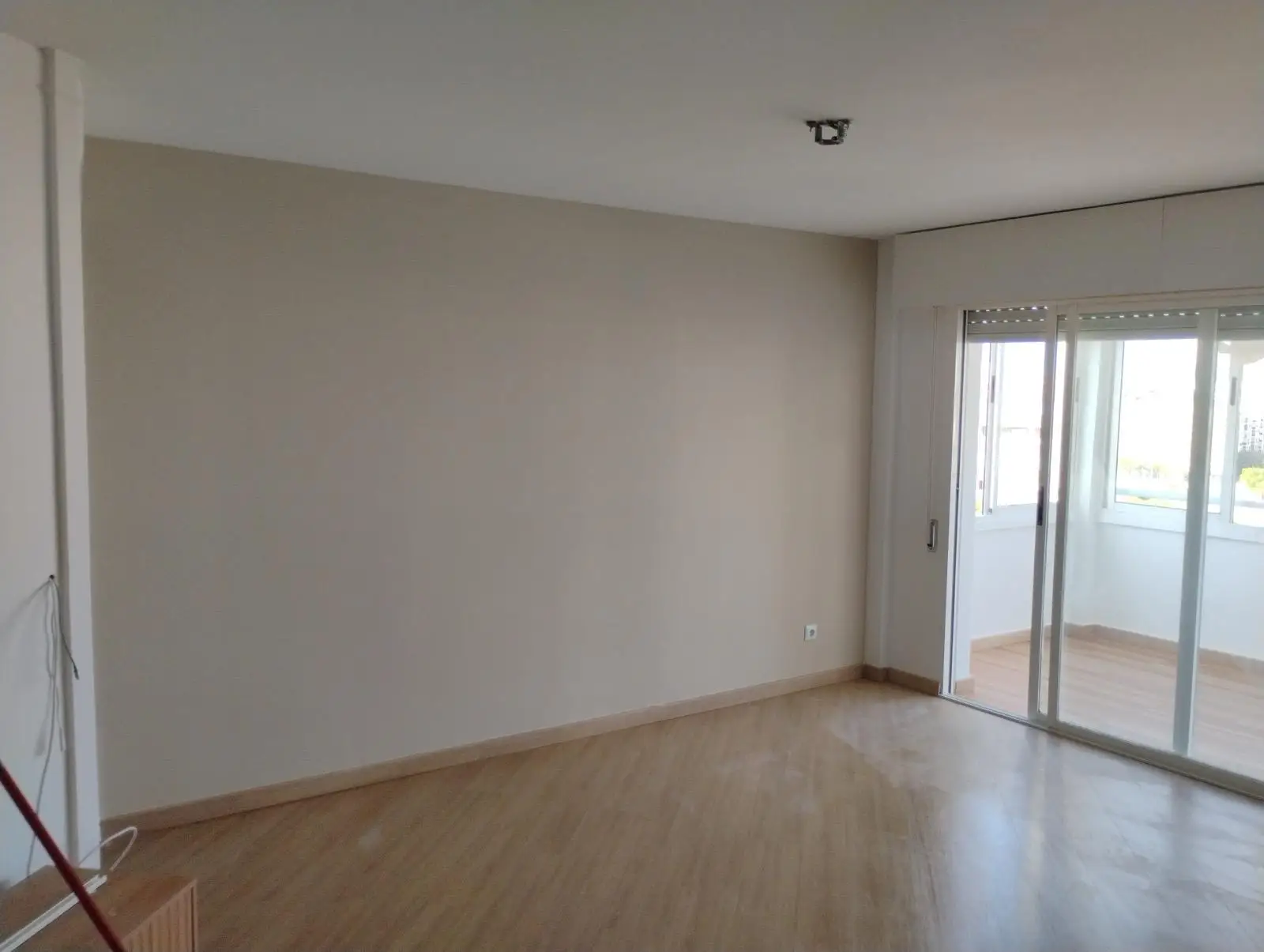 Reforma de vivienda con paredes beige, suelo de tarima clara y acceso a terraza en Madrid