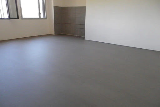 Reforma de vivienda con suelo continuo de microcemento gris y paredes blancas en Madrid